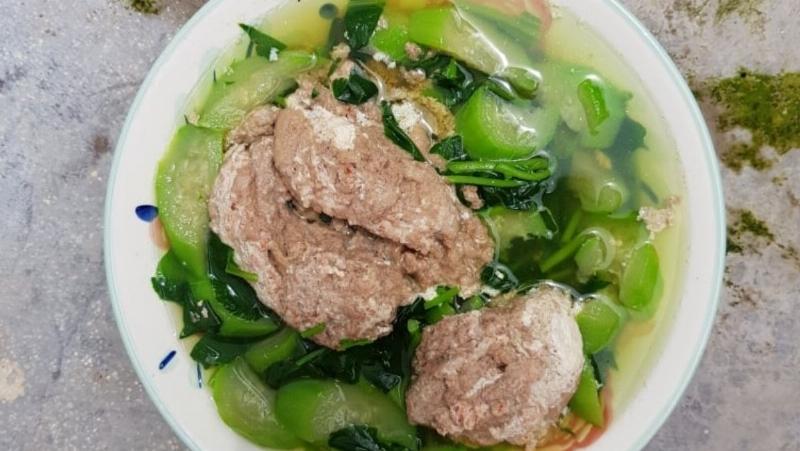 Nồi lẩu cua đồng sôi sùng sục cùng đĩa rau mồng tơi và rau đay tươi xanh mướt mát, chuẩn bị nhúng lẩu.