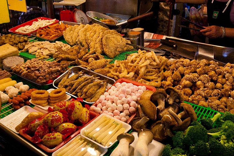 Một quầy hàng đường phố Hàn Quốc với nhiều loại xúc xích, tokbokki và đồ ăn vặt hấp dẫn